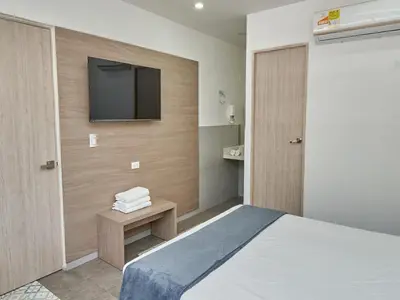 a hotel room with a bed and a flat screen tv at Stanza Hotel Medellin in Medellín