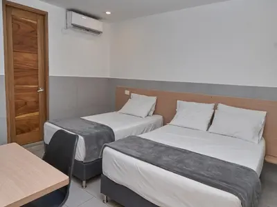 a hotel room with two beds and a table at Stanza Hotel Medellin in Medellín