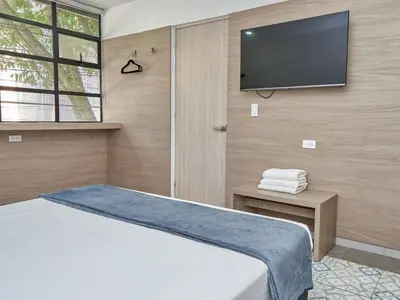 a bedroom with a bed and a flat screen tv at Stanza Hotel Medellin in Medellín