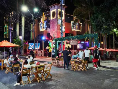 a group of people sitting at tables on a street at night at Stanza Hotel Medellin in Medellín