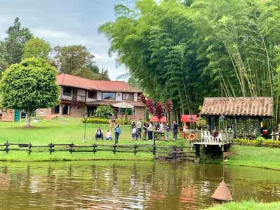 a group of people standing around a pond near a house at Rancheria Loft Chalet, lago privado in Rionegro
