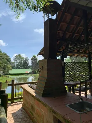 a patio with an outdoor fireplace in front of a lake at Rancheria Loft Chalet, lago privado in Rionegro