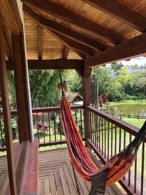 a hammock on a porch with a view of a park at Rancheria Loft Chalet, lago privado in Rionegro
