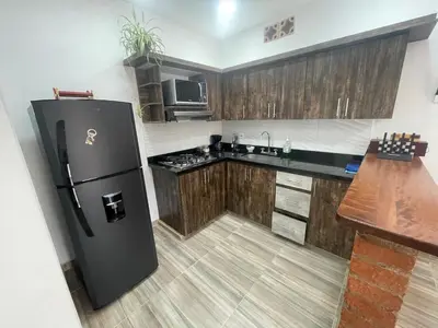 a kitchen with a black refrigerator and wooden cabinets at Apartamento cerca a cascada del Amor,Wifi in Jardin