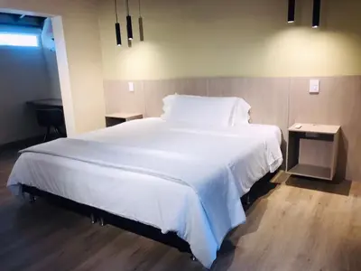a bedroom with a large white bed with two tables at Hotel & Golf Isak Aeropuerto in Rionegro
