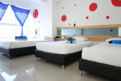 two beds in a room with red circles on the wall at HOTEL PORTÓN ESTADIO in Medellín