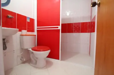 a red bathroom with a toilet and a shower at HOTEL PORTÓN ESTADIO in Medellín