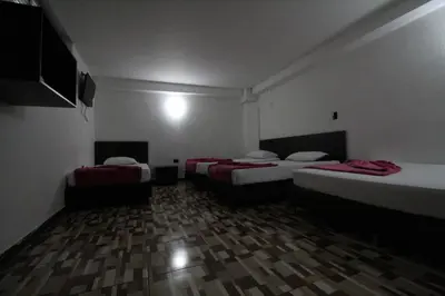 a room with three beds and a television in it at HOTEL PORTÓN ESTADIO in Medellín