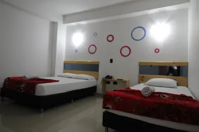 two beds in a room with red and blue circles on the wall at HOTEL PORTÓN ESTADIO in Medellín