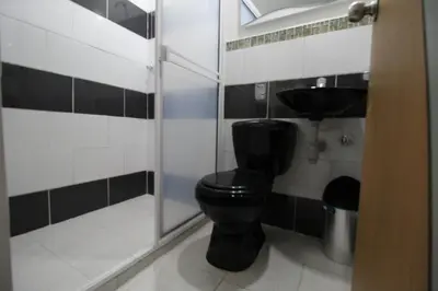 a bathroom with a black toilet and a shower at HOTEL PORTÓN ESTADIO in Medellín