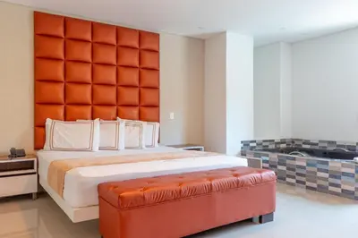a bedroom with a large bed with an orange padded headboard at Infinity Hotel in Medellín
