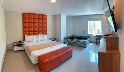 a bedroom with a large bed and a flat screen tv at Infinity Hotel in Medellín