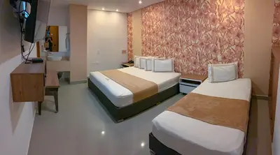 a hotel room with two beds and a television at Infinity Hotel in Medellín