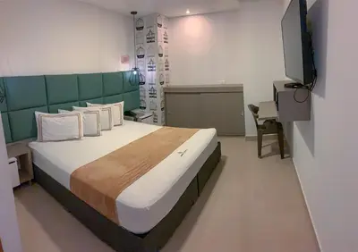 a bedroom with a large bed with a green headboard at Infinity Hotel in Medellín