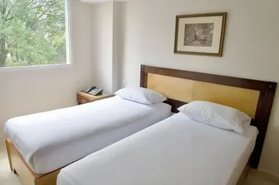 two beds in a hotel room with a window at Hotel San Pedro del Fuerte in Medellín