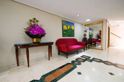 a living room with a red chair and a table with flowers on it at Hotel San Pedro del Fuerte in Medellín