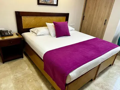 a bedroom with a large bed with a purple blanket at Hotel San Pedro del Fuerte in Medellín