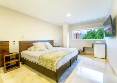 a bedroom with a large bed and a window at Hotel San Pedro del Fuerte in Medellín