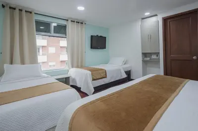 a hotel room with two beds and a window at Hotel Portón Sabaneta in Sabaneta