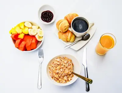 a white table with a breakfast of fruit and a cup of coffee at Gastón Coliving in Medellín