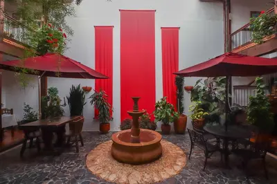 a courtyard with a fountain and tables and red umbrellas at Casa Lola Hotel Boutique in Salamina