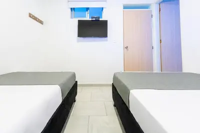 two beds in a room with a tv on the wall at Ayenda Panamericana in Manizales