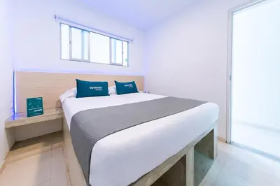 a bedroom with a large white bed with blue pillows at Ayenda Panamericana in Manizales