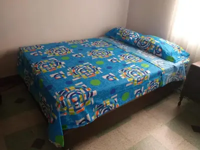 a bed in a room with a blue comforter at Big House Medellin in Medellín