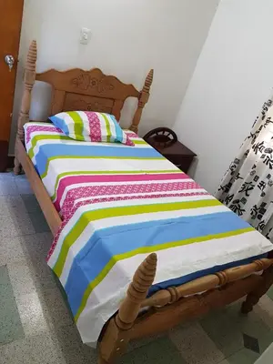 a wooden bed with a colorful striped comforter in a room at Big House Medellin in Medellín