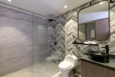 a bathroom with a toilet and a sink and a mirror at Factory Lofts Hotel in Medellín