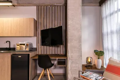 a kitchen with a table with a television on a wall at Factory Lofts Hotel in Medellín