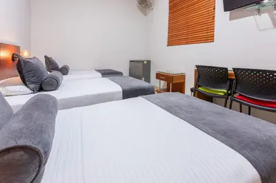a hotel room with three beds and chairs at Hotel Sauces del Estadio in Medellín