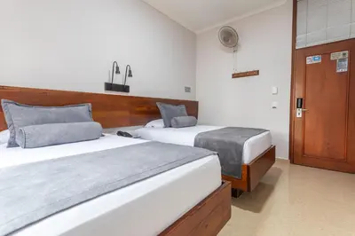 a hotel room with two beds and a door at Hotel Sauces del Estadio in Medellín