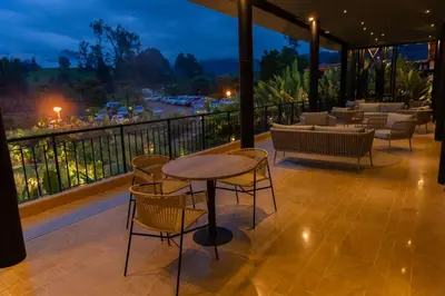 a patio with a table and chairs on a balcony at Termales El Otoño in Manizales