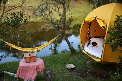 a tent next to a river with a table and a bed at Glamping Ancestros Ecoparque in Girardota