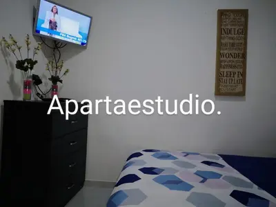a bedroom with a bed and a tv and a dresser at Cómodos y acogedores Apartaestudios - Manizales in Manizales