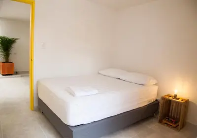 a bedroom with a bed with white sheets and a lamp at Home Aris Apartments 201 in Medellín