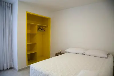 a bedroom with a white bed and a yellow shelf at Home Aris Apartments 201 in Medellín