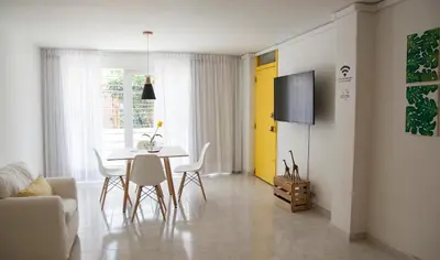 a living room with a table and chairs and a yellow door at Home Aris Apartments 201 in Medellín