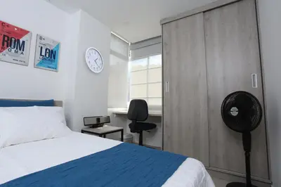 a bedroom with a bed and a door with a clock at New Studio Apartment for Two in Medellín