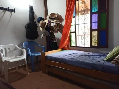 a bedroom with a bed and a chair and a window at Finca Alejandria (Condominio la Chiquita) in Marinilla
