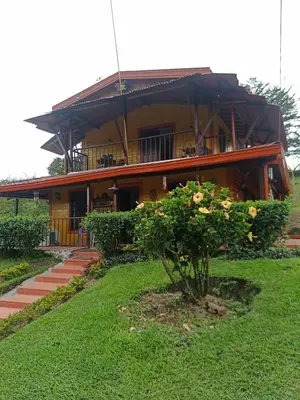 a house with a tree in front of it at Finca Alejandria (Condominio la Chiquita) in Marinilla