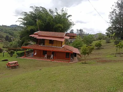 a small house with a red roof on a field at Finca Alejandria (Condominio la Chiquita) in Marinilla