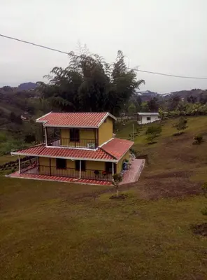 a yellow house with a red roof in a field at Finca Alejandria (Condominio la Chiquita) in Marinilla
