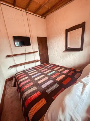 a bedroom with a bed with a quilt on it at Las Orquídeas EcoHostel in Guarne