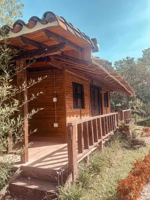 a wooden cabin with a porch and a fence at Las Orquídeas EcoHostel in Guarne