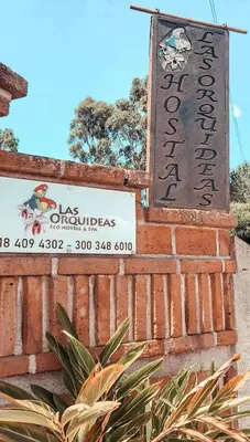 a sign on the side of a brick wall with a sign at Las Orquídeas EcoHostel in Guarne