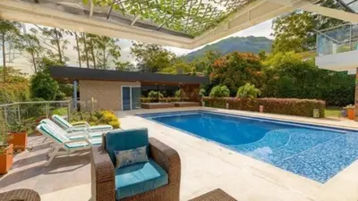 a swimming pool in a backyard with a patio furniture and a house at Libertg Hotels Medellin in Copacabana