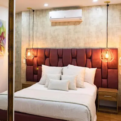 a bedroom with a large bed with a red padded headboard at Libertg Hotels Medellin in Copacabana