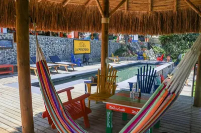 a couple of chairs and a hammock next to a pool at Finca La Manchuria in Salgar